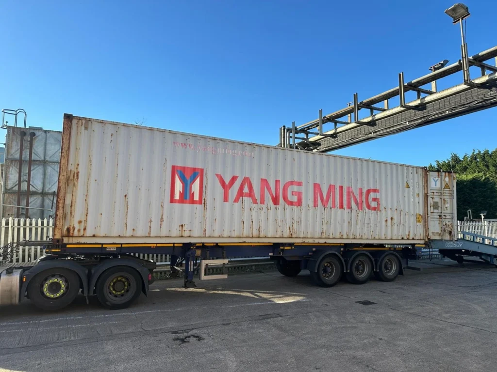 Side view of shipping container loading at export site, for FCL to USA