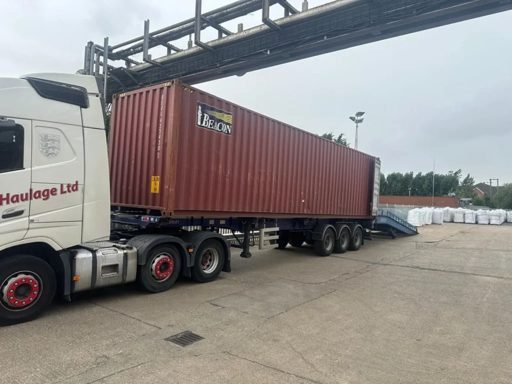 Shipping container on the back of a truck, loading with a ramp for sea freight to the USA from the UK