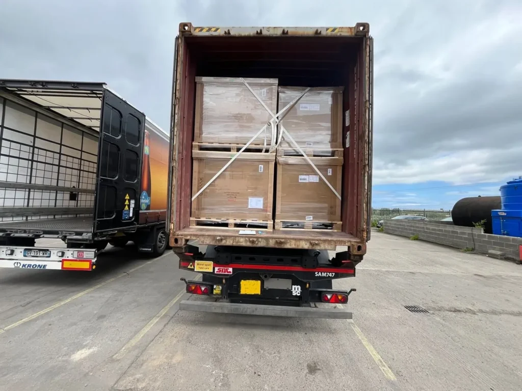 Shipping container on the back of a truck, rear view with doors open, loaded and lashed stacks of pallets for shipping to Australia