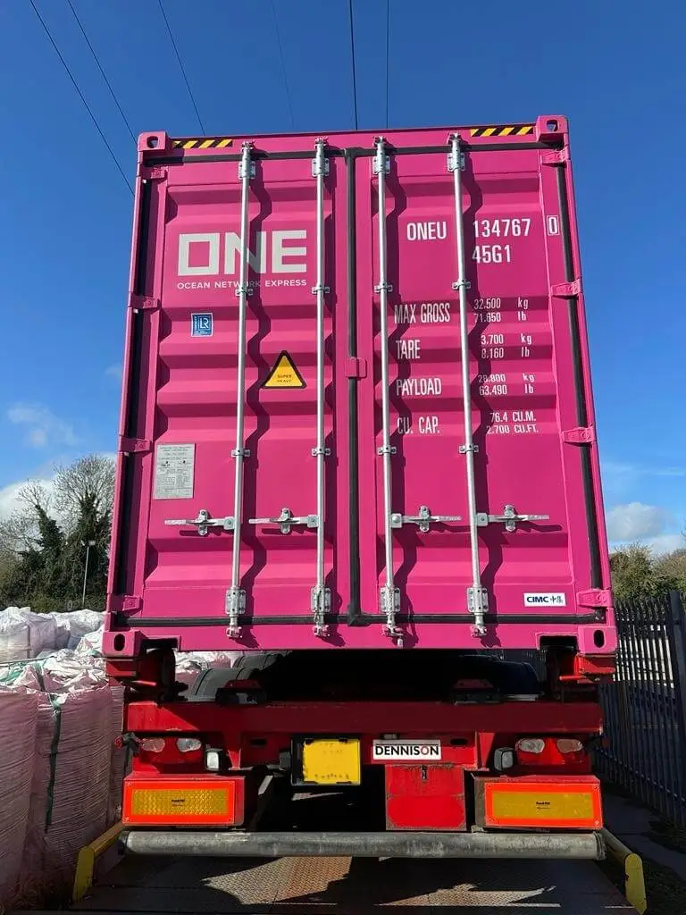 Pink shipping container on a truck, rear view, doors closed for sea freight from Thailand